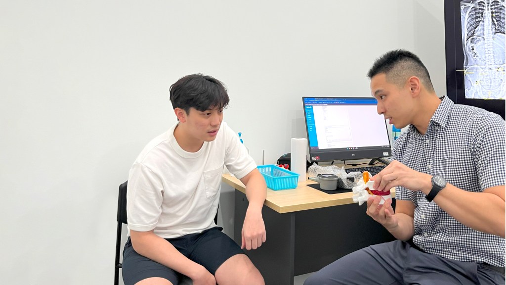 Dr Kit consulting a chiropractic patient.